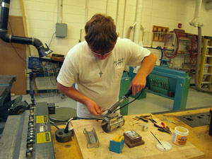 Soldering handle hinge assembly to lens cylinder.
